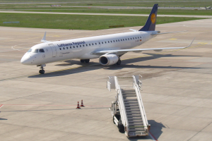 Ein Lufthansa-Regional-Airbus A320-200 auf der Rollbahn am Frankfurter Airport, umgeben von Verkehrskegeln und einem Fahrzeug mit Treppe, mit saftig grünem Gras, Bäumen und einem klaren blauen Himmel im Hintergrund.