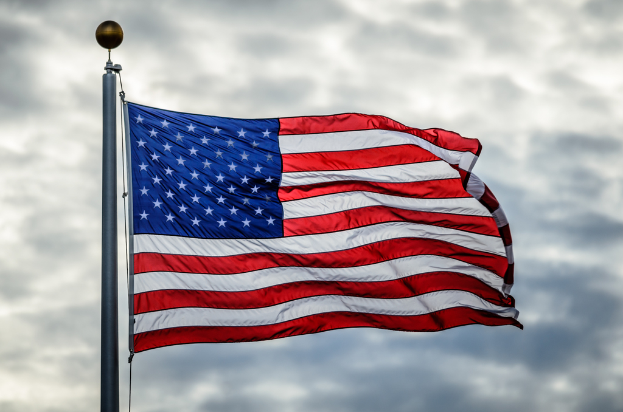 Die Flagge der USA weht an einer Fahnenstange gegen einen bewölkten Himmel.
