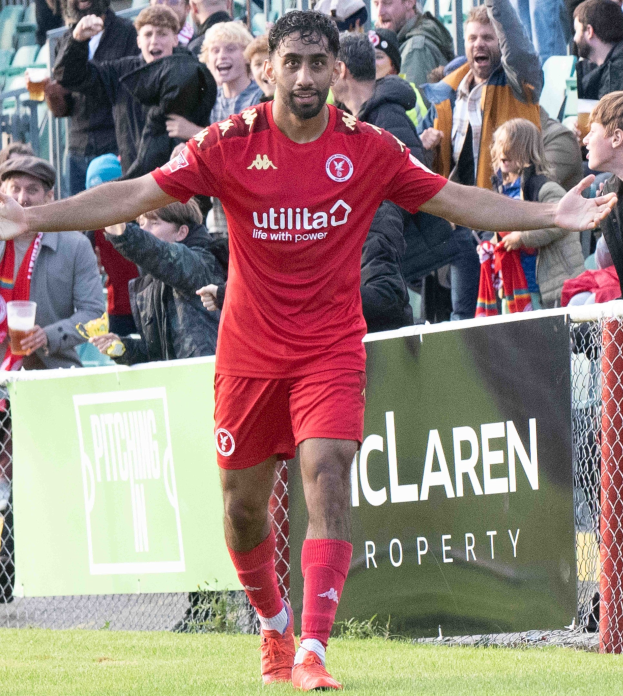 Ein Fußballspieler in roter Uniform rennt mit ausgestreckten Armen auf einem Feld, umgeben von Zuschauern hinter einem Zaun, mit einem "Middlesbrough FC v Swansea City - Sky Bet Championship"-Schild im Hintergrund.
