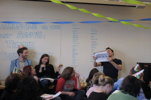 Eine Gruppe von Menschen feiert ihren ersten jährlichen Thesendurchgang, mit Bändern auf dem Dach und einigen Personen mit Mützen.