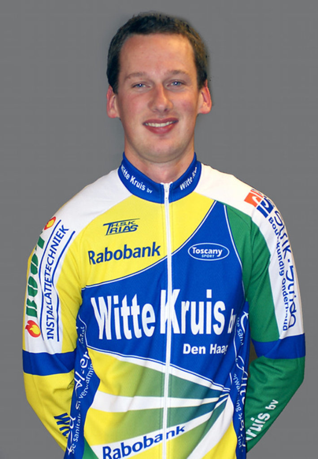 Ein Sportler, der f├╝r ein Foto posiert und ein T-Shirt mit verschiedenen Sponsorennamen tr├Ągt.