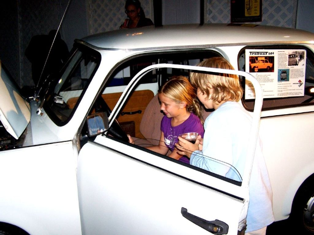 Zwei Kinder versuchen, in ein Auto mit anderen Menschen in der Nähe einzusteigen.