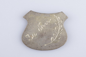 Silbernes Abzeichen mit einem Lorbeerkranz und der Aufschrift "50. Hochzeitstag" auf einem weißen Hintergrund.