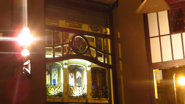 Ein GebÃ¤ude mit Gittern, Plakaten und Lichtern drumherum.