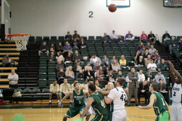 Ein Basketballfeld mit spielenden Spielern und Zuschauern im Hintergrund