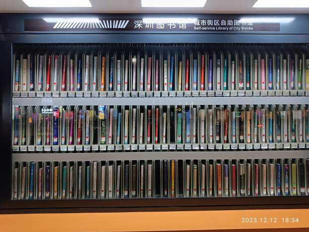 Eine gut beleuchtete Bibliothek mit hohen Bücherregalen voller Bücher, ein Textbrett und ein Wasserzeichen unten, das an eine Selbstbedienungsbibliothek der Stadtblocks erinnert.