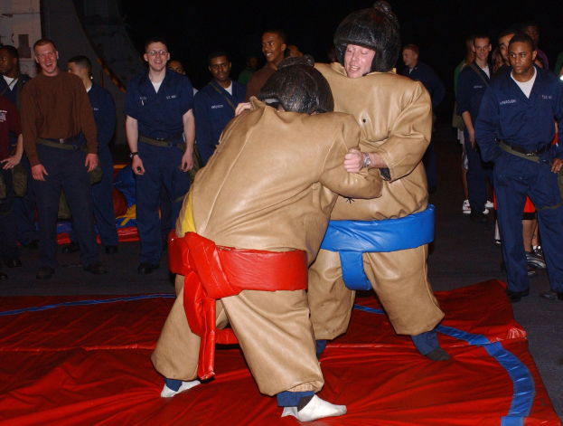 Zwei Sumo-Ringer, die auf einer roten Matte kämpfen.