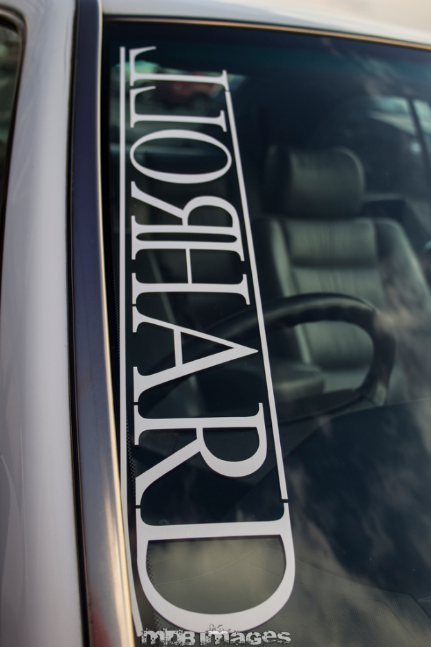 Windschutzscheibe eines Autos mit Text, durch die Scheibe sind Lenkrad und Sitze zu sehen.