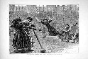 Eine Schwarz-Weiß-Radierung von Kindern, die mit einem Ball in einer Turnhalle spielen, mit zwei Mädchen in der Mitte, die Stöcke halten, und einem Text unten, der "Eine Damenklasse im Deutschen Turnverein" lautet.