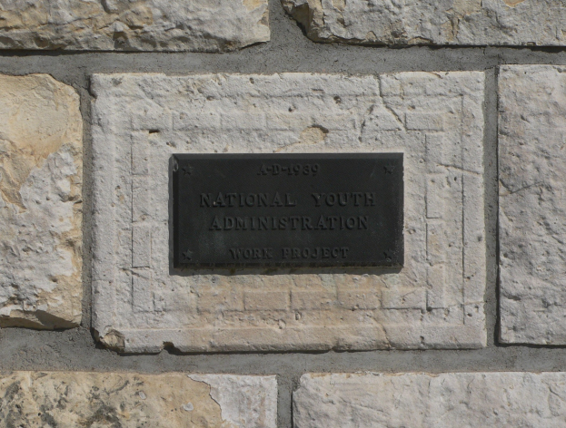 Steinwand mit einem rechteckigen Schild, auf dem in fetten weißen Buchstaben "National Youth Administration" steht.