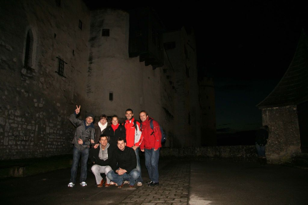Menschen stehen in der Mitte eines Bildes mit einem Schloss im Hintergrund bei Nacht.