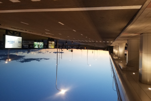 Ein Hallenbad mit Säulen auf der rechten Seite, mit einer Decke mit Lichtern und Bildschirmen im Hintergrund.