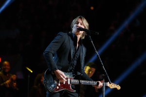 Keith Urban performs auf der Bühne im Joint am Hard Rock Hotel & Casino in Las Vegas, spielt Gitarre mit einem Mikrofon vor sich und Bandmitgliedern im Hintergrund bei gedämpfter Beleuchtung.