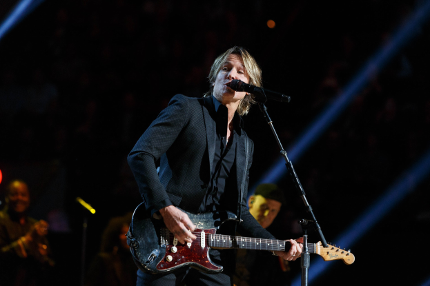 Keith Urban performs auf der Bühne im Joint am Hard Rock Hotel & Casino in Las Vegas, spielt Gitarre mit einem Mikrofon vor sich und Bandmitgliedern im Hintergrund bei gedämpfter Beleuchtung.