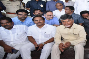 Andhra Pradesh Chief Minister Chandrababu Naidu und seine Kabinettsmitglieder versammeln sich zu einer Besprechung in Hyderabad, wobei einige Teilnehmer auf einer Treppe sitzend mit Mobiltelefonen und andere im Hintergrund stehend zu sehen sind.