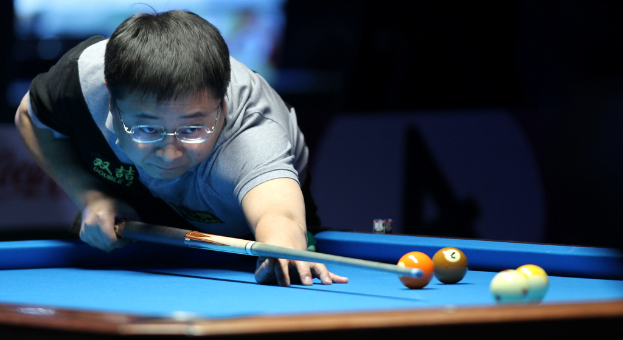 Eine Person mit einem Queue-Stock beim Snooker-Spielen, mit mehreren Bällen auf dem Tisch.