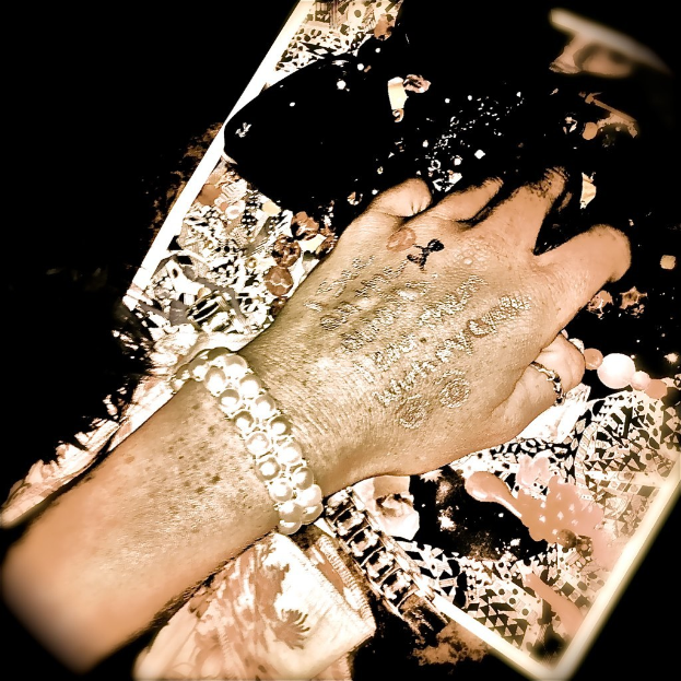 Eine Hand mit Text darauf, die Schmuck trägt.
