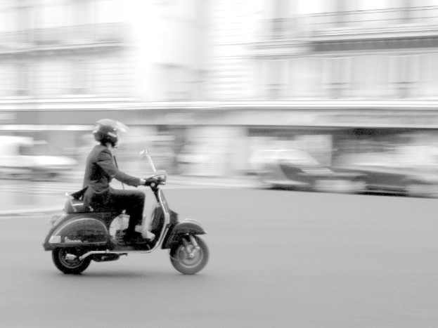 Eine Person fährt Roller auf der Straße.