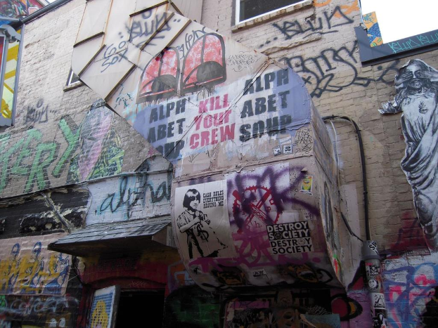 Eine Wand, die mit Graffiti und Postern von Menschen bedeckt ist, mit einer Tür auf der rechten Seite.