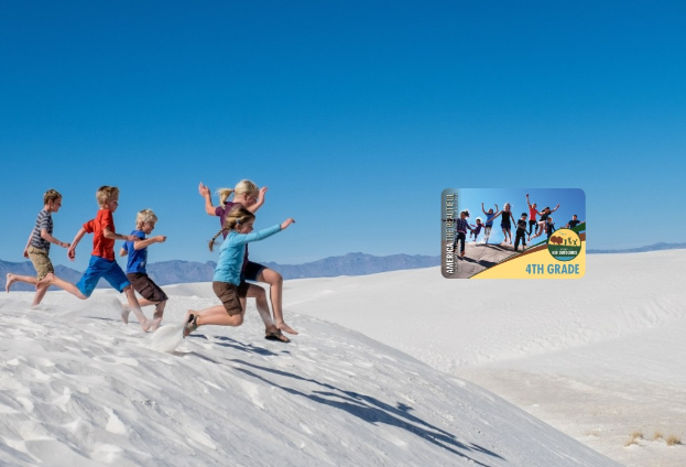 Gruppe von Kindern, die über eine weiße Sanddüne in Death Valley National Park laufen, mit Hügeln im Hintergrund und einem klaren blauen Himmel, mit einer Anzeige für ein 4. Schuljahr-Abenteuer auf der rechten Seite.