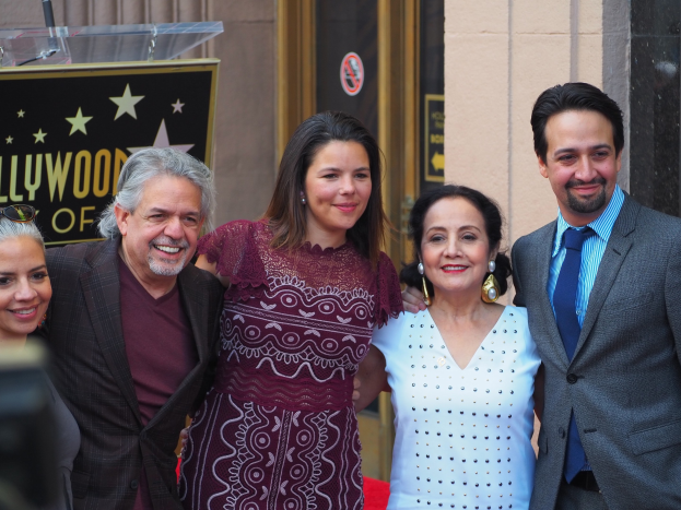 Gruppe von Menschen auf einem roten Teppich bei der Zeremonie des Hollywood Walk of Fame mit einer Tafel, einem Glaspodest und einer Wand im Hintergrund.