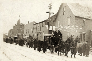Menschen auf einem Schneepfad mit einigen auf Pferdewagen, Gebäuden, Polen und Text auf der rechten Seite.