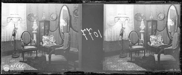 Ein Schwarz-Weiß-Foto eines möblierten Raums mit Stühlen, Kissen, Lampen, Schränken, Spiegeln, Vorhängen und anderen Gegenständen, das ein Vintage-Wasserzeichen aufweist.