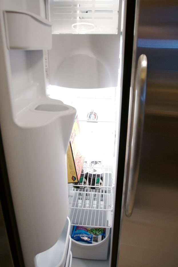 Ein Kühlschrank mit Wasserflaschen und Packungen darin, mit einem unscharfen Hintergrund.