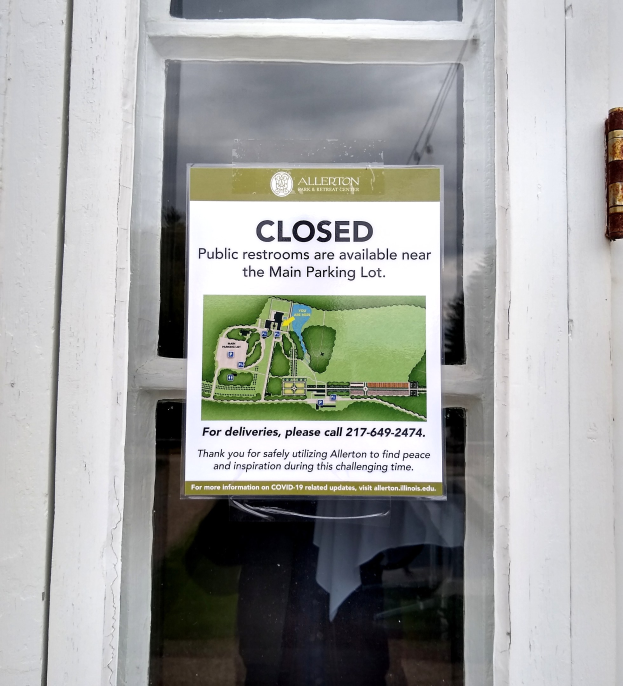 Glasstür mit einem Schild "Geschlossene öffentliche Toiletten verfügbar in der Nähe des Hauptparkplatzes" und einem undeutlichen Objekt auf der rechten Seite.