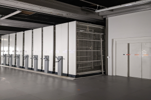 Ein großer Raum voller numerous Server, mit einem Boden, einer Wand auf der rechten Seite und einer Decke mit Leuchten oben, was auf ein Datenzentrum hinweist.