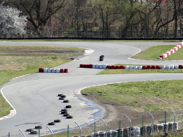 Rennstrecke übersät mit Reifen, umgeben von Gras und Maschendrahtzaun, mit Bäumen im Hintergrund.
