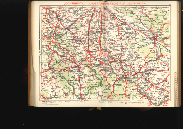 Ein aufgeschlagenes Buch, das eine detaillierte Karte von Deutschland mit Straßen und Autobahnen zeigt, vor einem schwarzen Hintergrund.