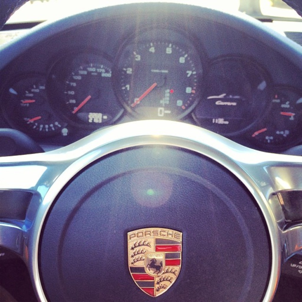 Eine Nahaufnahme des Armaturenbretts eines Porsche-Fahrzeugs, das den Tacho und das Lenkrad zeigt.