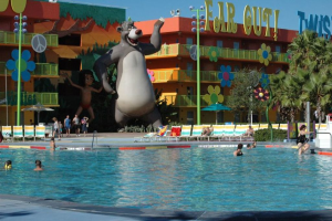 Ein Schwimmbad mit blauem Wasser und Menschen darin, mit Cartoon-Bildern und Polen im Hintergrund.