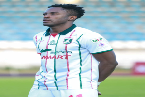 Der ghanaische Fußballspieler Emmanuel Adebayor steht auf einem Fußballfeld in einem weißen und grünen T-Shirt und Shorts und hat einen unscharfen Hintergrund.