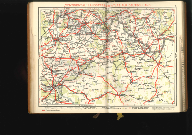 Offenes Buch zeigt detaillierte Karte von Deutschlands Straßen und Autobahnen auf schwarzem Hintergrund.
