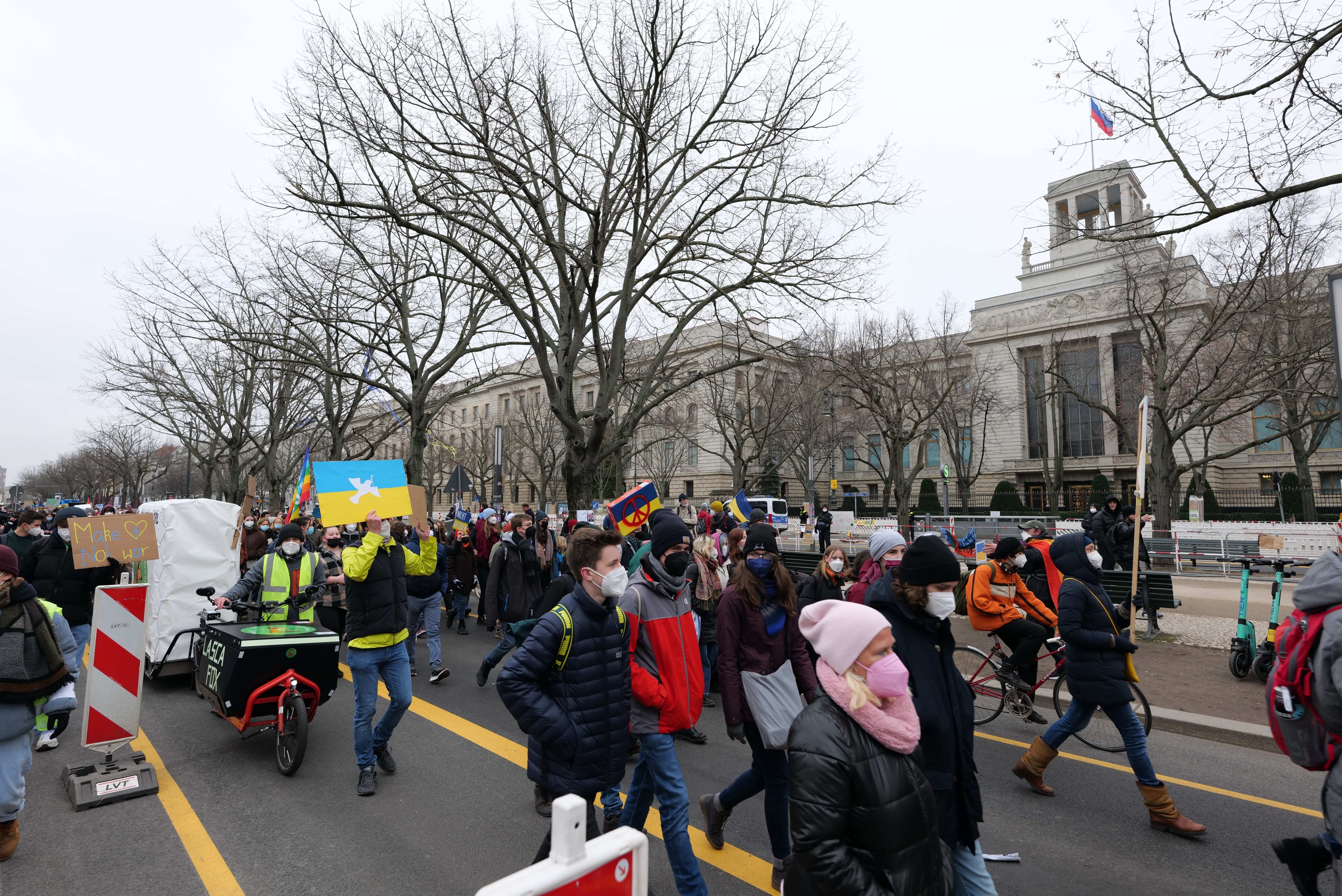 Eine große Gruppe von Menschen marschiert auf einer Stadtstraße bei einer Demonstration, einige halten Schilder und andere fahren Fahrräder, mit Bäumen und Gebäuden im Hintergrund an einem klaren blauen Himmel in Washington, D.C. am 21. Januar 2020.