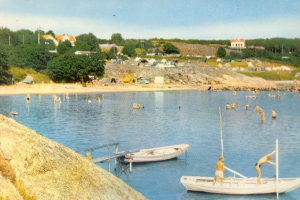 Ein altes Foto von Menschen, die in der Nähe eines Bootes schwimmen, mit einer Brücke mit Geländern im Vordergrund und einem Felsen auf der linken Seite, mit Bäumen, Gebäuden, Fahrzeugen, Pfählen und einem bewölkten Himmel im Hintergrund.