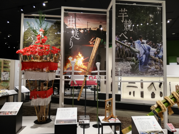 Ein Raum voller verschiedener Gegenstände, darunter Schilder mit Text, Ständer und andere Objekte, mit Schildern mit Bildern und Text sowie Deckenleuchten, die eine festliche Atmosphäre für die Tokyo Toy Fair 2019 schaffen.