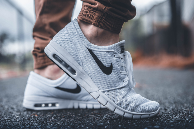 Nahaufnahme einer Person, die Nike SB Stefan Janoski Max Schuhe in Wolf Grey/Black-White trägt, vor einem unscharfen Hintergrund.
