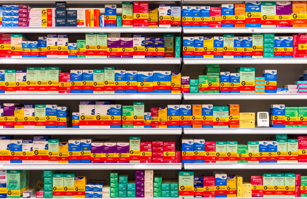 Ein Regal in einer Apotheke, das mit verschiedenen Medikamenten, darunter Schachteln, gefüllt ist, die ordentlich auf den Regalen angeordnet sind.