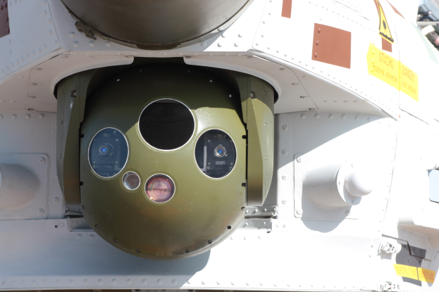 Nahaufnahme eines Militärfahrzeugs mit einer runden, grünen und weißen Rakete, die seitlich an einem Metallrahmen montiert ist.
