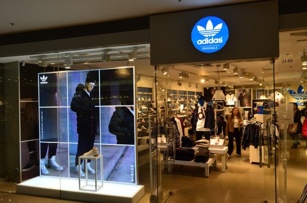 Ein Adidas-Laden in einem Einkaufszentrum mit Schaufensterpuppen, Kleidung, Schuhen und einer Plakette mit dem Adidas-Logo für Adidas Originals.