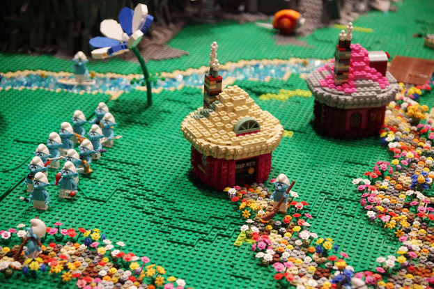 Ein Lego-Modell einer Kleinstadt mit Blumen, Spielzeugen, Häusern, Pflanzen und anderen Gegenständen, mit einem leicht unscharfen Hintergrund für ein träumerisches Gefühl.