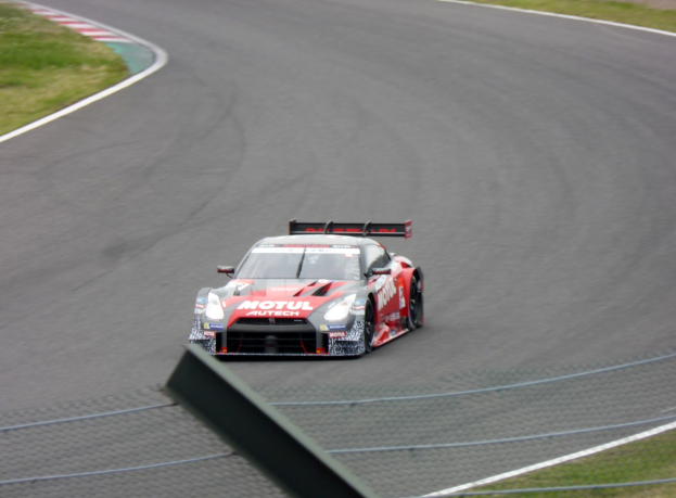 Ein Nissan GT-R Nismo GT3 Rennauto auf der Nürburgring 24 Stunden Rennstrecke, mit grünem Gras auf beiden Seiten der Straße.
