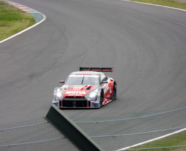 Ein Nissan GT-R Nismo GT3 Rennauto auf der Nürburgring 24 Stunden Rennstrecke, mit grünem Gras auf beiden Seiten der Straße.