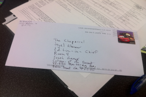 Ein Tisch mit Papier, einer Datei, einem Brief, einem Stift und einem unbekannten Objekt darauf.