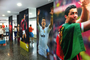 Ein Banner mit dem Fussballspieler Rolando, umgeben von Menschen an einem Tisch auf der linken Seite und Lichtern oben.