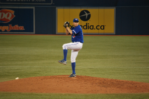 Ein Spieler steht auf dem Feld und hält einen Ball in der Hand, im Hintergrund ist eine große Fahne mit Text und Bildern zu sehen.
